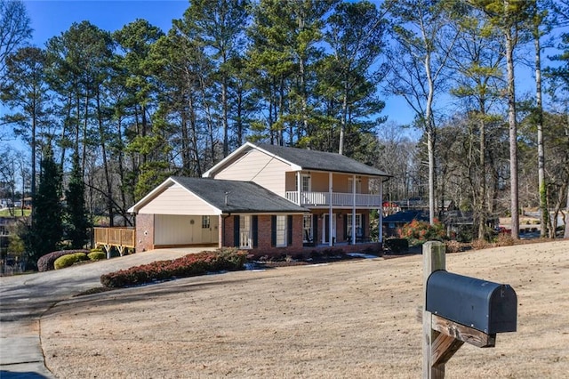 view of front facade featuring a balcony, driveway, and brick siding