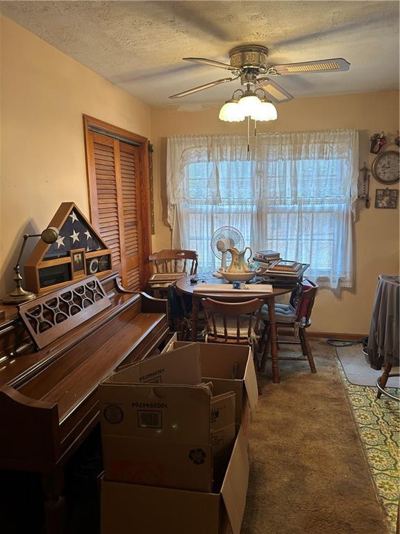 dining room featuring a textured ceiling, ceiling fan, and carpet flooring