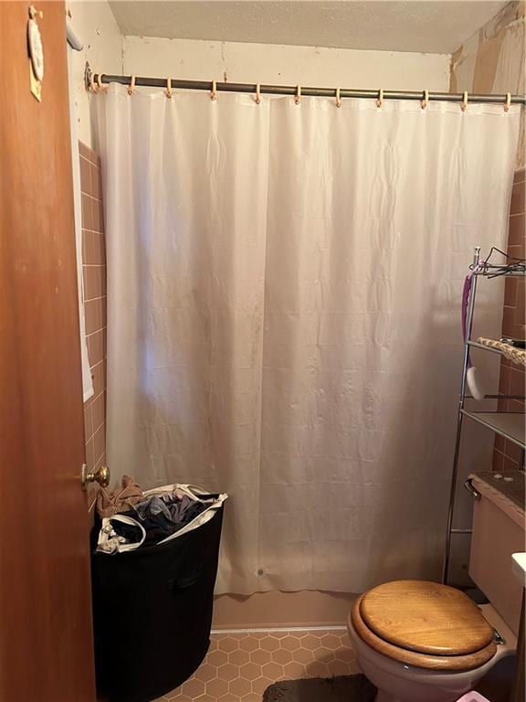 bathroom featuring curtained shower, toilet, and tile patterned flooring