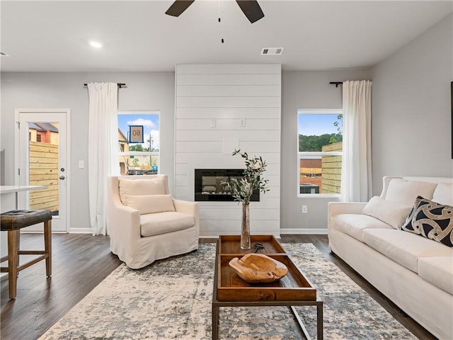 living room featuring a fireplace, ceiling fan, and dark hardwood / wood-style floors