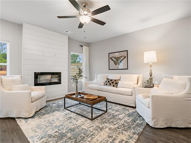 living room featuring a fireplace, ceiling fan, and wood-type flooring