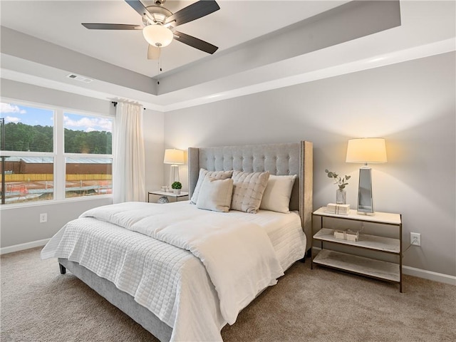 carpeted bedroom featuring ceiling fan and a tray ceiling