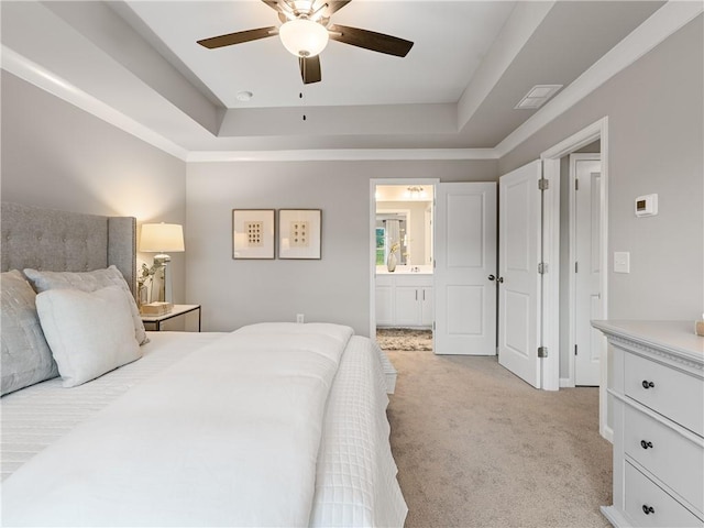 bedroom with ensuite bath, light colored carpet, ceiling fan, and a tray ceiling