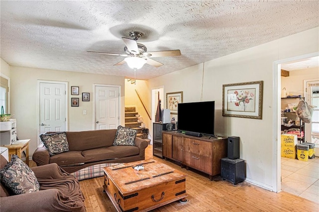 living room featuring ceiling fan, a textured ceiling, and light wood-type flooring