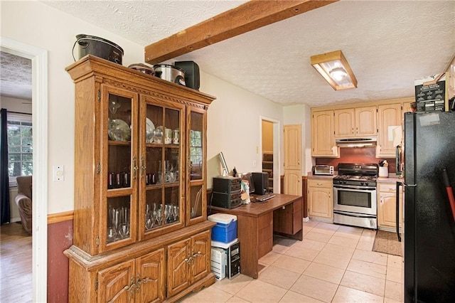 kitchen featuring black fridge, a textured ceiling, light tile patterned floors, stainless steel range with gas cooktop, and beamed ceiling