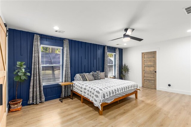 bedroom with ceiling fan, multiple windows, and light wood-type flooring