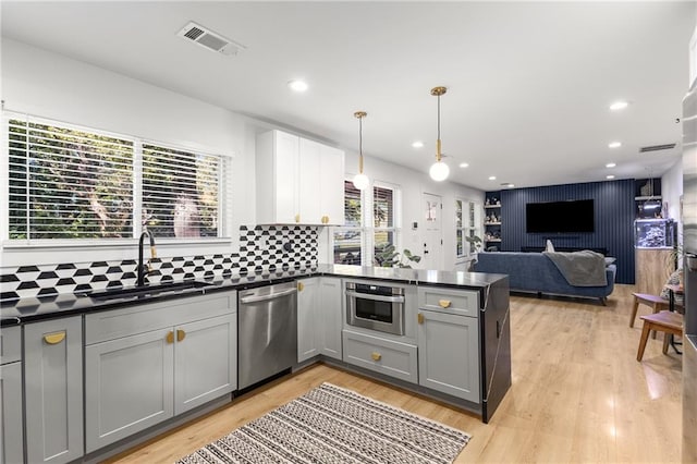 kitchen featuring pendant lighting, appliances with stainless steel finishes, sink, tasteful backsplash, and gray cabinetry