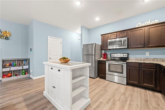 kitchen featuring appliances with stainless steel finishes, dark brown cabinetry, light stone countertops, and light hardwood / wood-style flooring