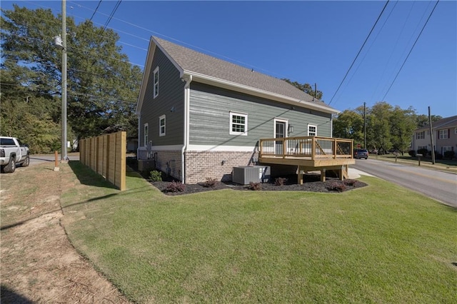 exterior space with a wooden deck, a yard, and central AC