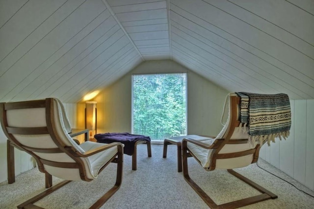 living area featuring carpet floors, vaulted ceiling, and wooden walls