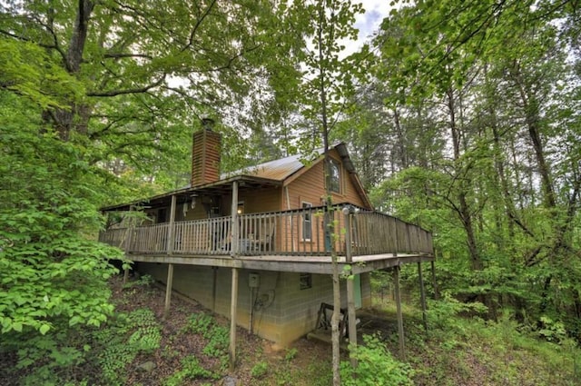 rear view of property featuring a chimney and a wooden deck