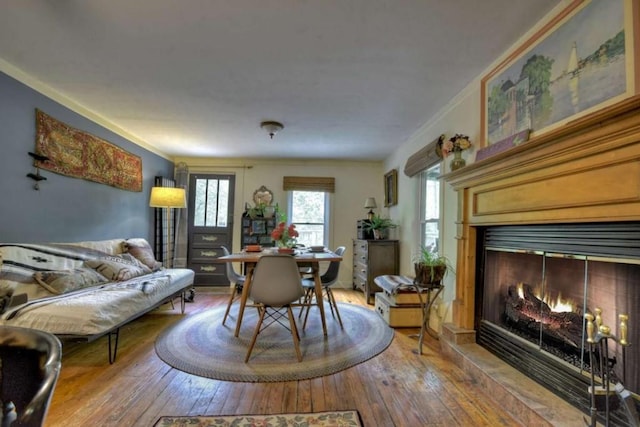 dining space featuring a glass covered fireplace, hardwood / wood-style flooring, and crown molding