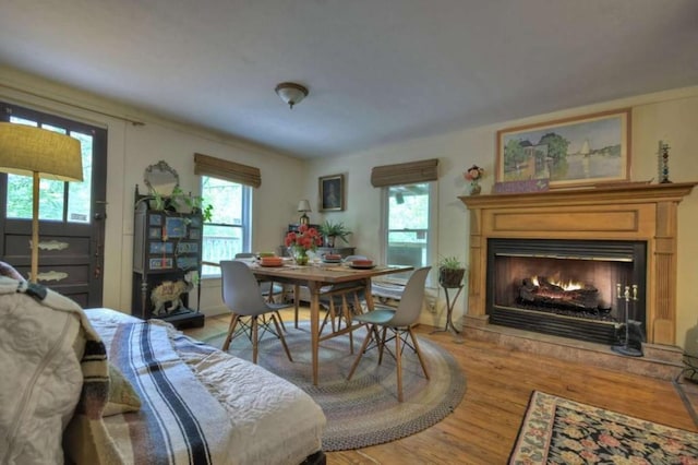 dining space with light wood-style flooring and a warm lit fireplace