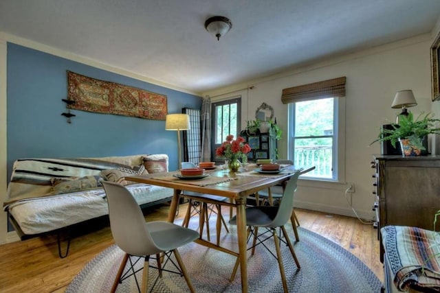 dining room with baseboards, light wood-style flooring, and ornamental molding