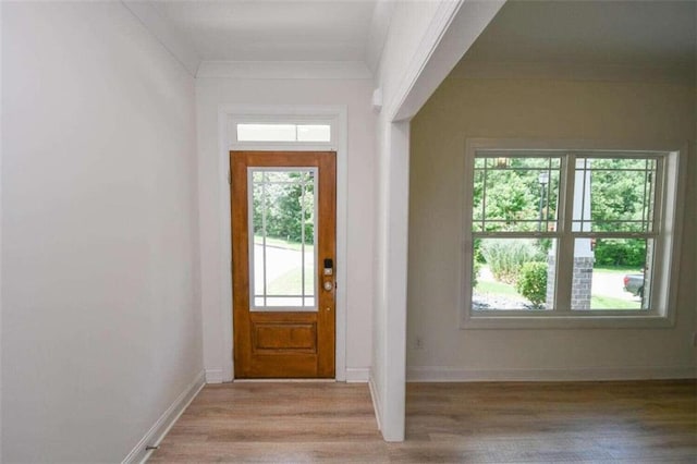 doorway with plenty of natural light, ornamental molding, and light wood-type flooring