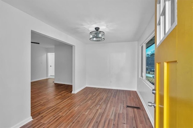 unfurnished room featuring hardwood / wood-style flooring and an inviting chandelier