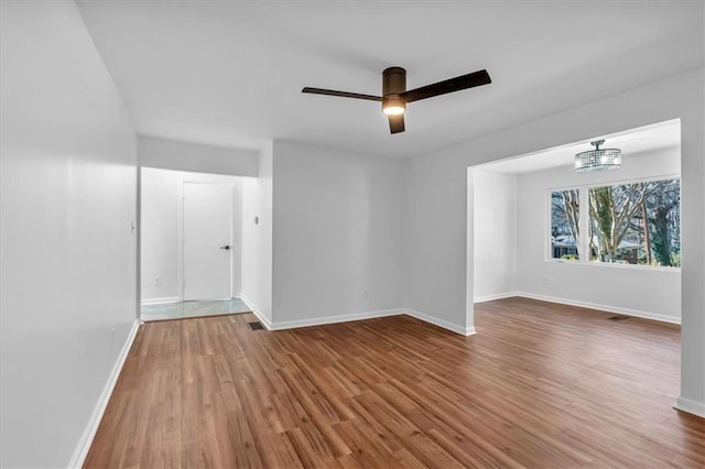 spare room with wood-type flooring and ceiling fan with notable chandelier