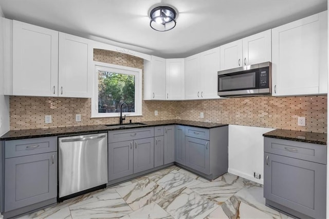 kitchen featuring dark stone counters, sink, white cabinets, and stainless steel appliances