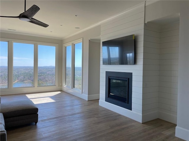 unfurnished living room featuring ornamental molding, dark hardwood / wood-style floors, ceiling fan, and a water view