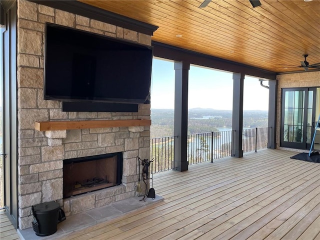 wooden terrace with ceiling fan and an outdoor stone fireplace