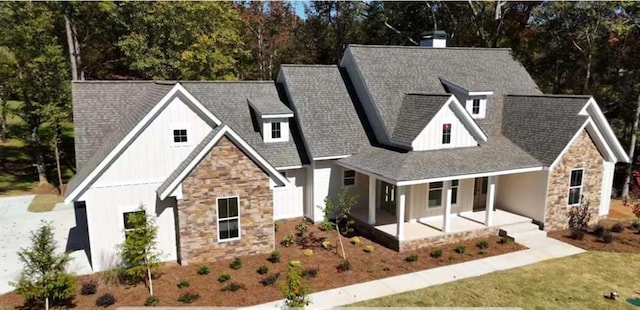 modern inspired farmhouse featuring covered porch, stone siding, a shingled roof, and board and batten siding