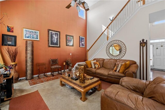 carpeted living room featuring ceiling fan and a towering ceiling