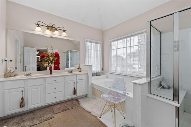 bathroom featuring vanity, vaulted ceiling, and independent shower and bath