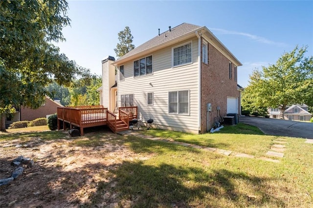 back of property with a lawn, central AC unit, a garage, and a wooden deck