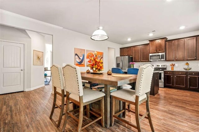dining space with baseboards, recessed lighting, ornamental molding, and light wood finished floors