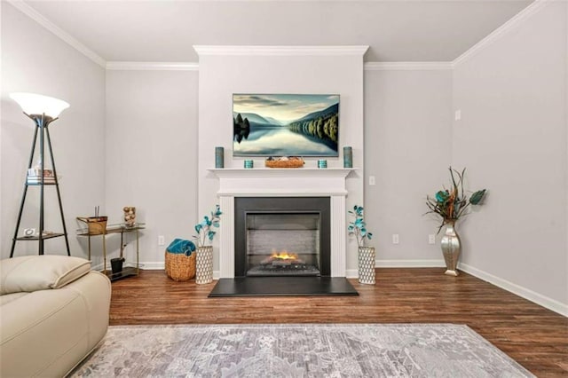 living area featuring baseboards, wood finished floors, a lit fireplace, and ornamental molding