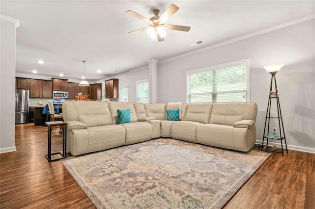 living room with ceiling fan, dark wood-type flooring, crown molding, visible vents, and baseboards