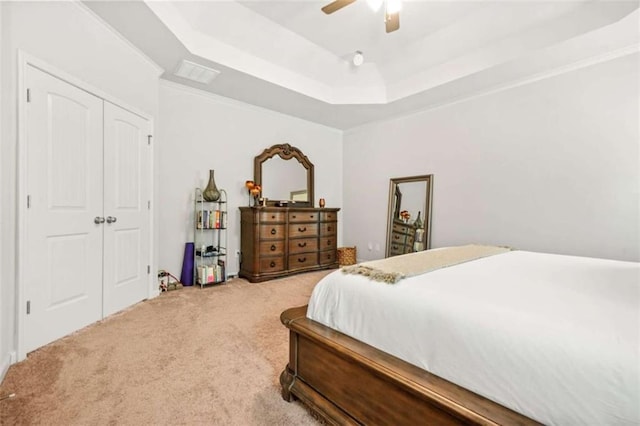 bedroom with carpet floors, a closet, ceiling fan, visible vents, and a tray ceiling
