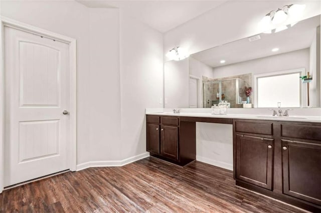 full bathroom featuring wood finished floors, a shower stall, double vanity, and a sink