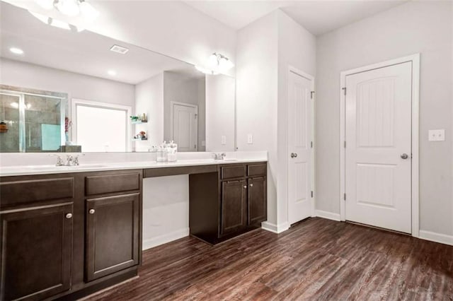 full bath with double vanity, a sink, a shower stall, and wood finished floors