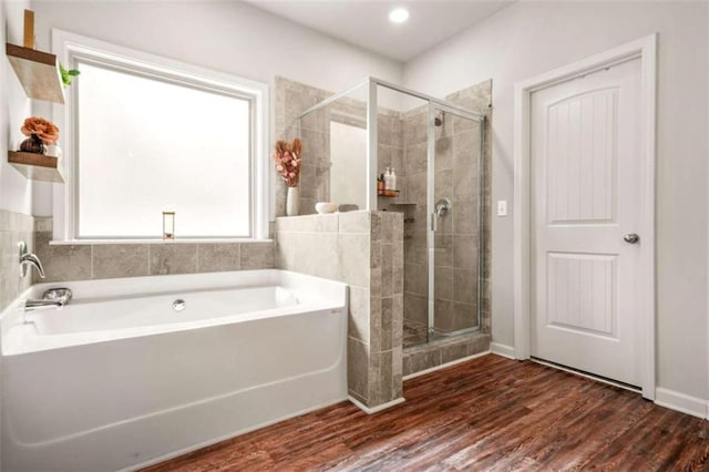 bathroom featuring a stall shower, a bath, and wood finished floors