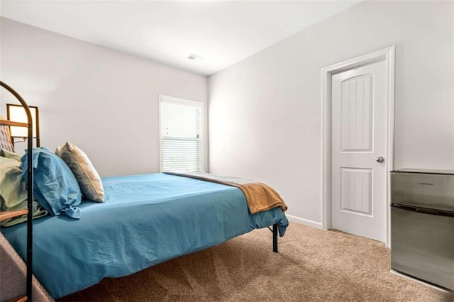 carpeted bedroom with visible vents and freestanding refrigerator