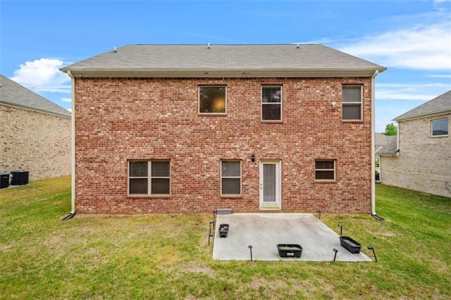 back of property with a lawn, brick siding, and a patio area
