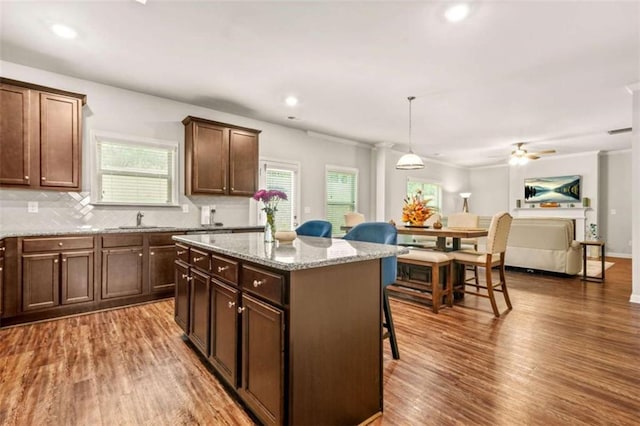 kitchen featuring a breakfast bar, a center island, wood finished floors, and tasteful backsplash