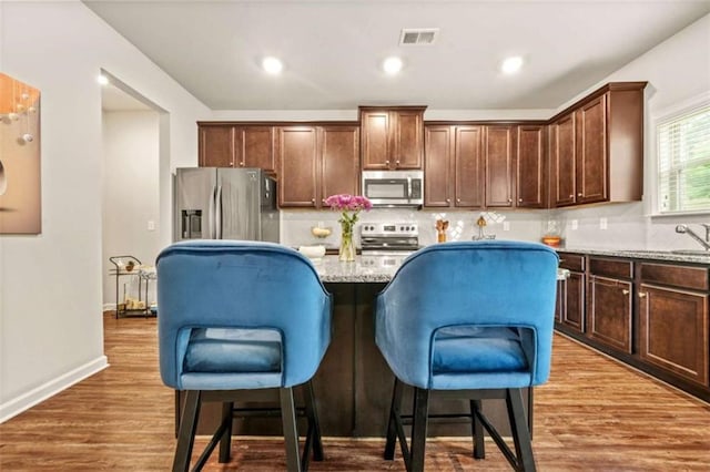kitchen featuring appliances with stainless steel finishes, a breakfast bar, a kitchen island, and backsplash