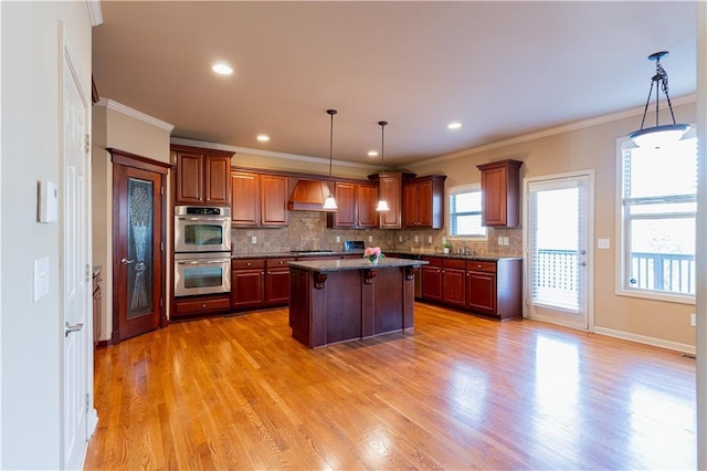 kitchen with stainless steel double oven, a center island, backsplash, custom range hood, and pendant lighting