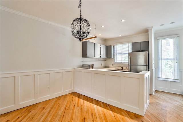 kitchen featuring light hardwood / wood-style flooring, decorative light fixtures, a healthy amount of sunlight, and stainless steel refrigerator