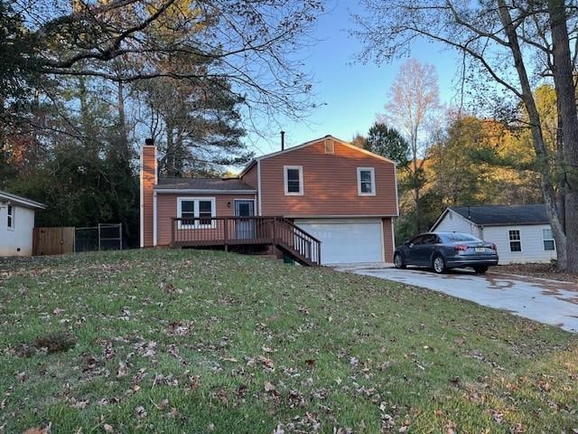 view of front of home featuring a wooden deck, a front lawn, and a garage