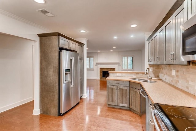 kitchen with sink, decorative backsplash, light hardwood / wood-style floors, and appliances with stainless steel finishes