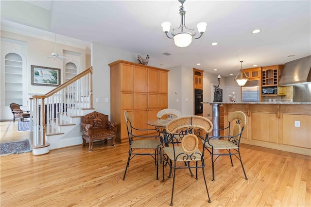 dining area featuring built in features, light hardwood / wood-style flooring, and a notable chandelier