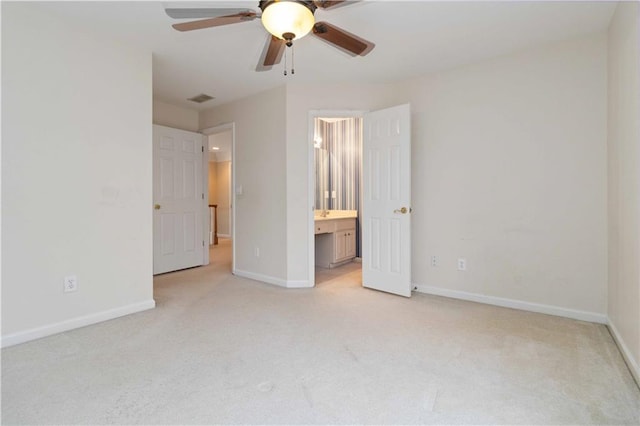 unfurnished bedroom featuring light colored carpet, ensuite bath, and ceiling fan