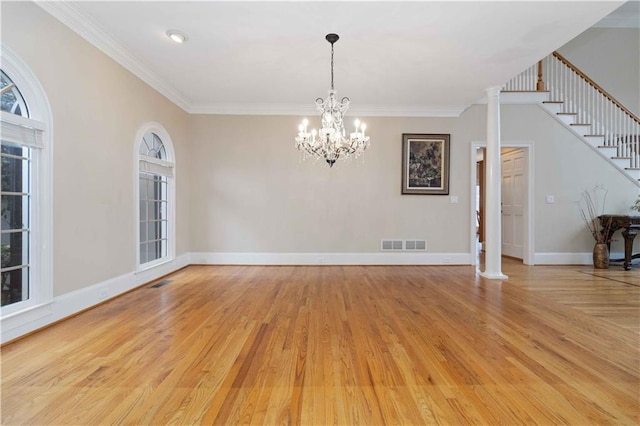 unfurnished room with decorative columns, light hardwood / wood-style floors, an inviting chandelier, and ornamental molding