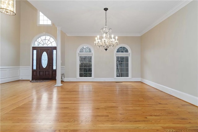 entryway with decorative columns, light hardwood / wood-style floors, a notable chandelier, and ornamental molding