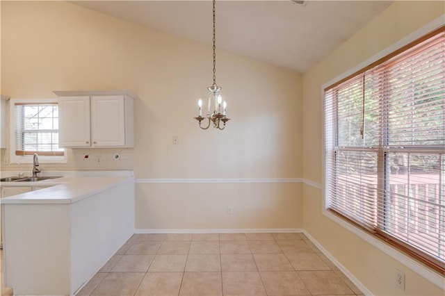 unfurnished dining area with light tile patterned floors, baseboards, lofted ceiling, a chandelier, and a sink