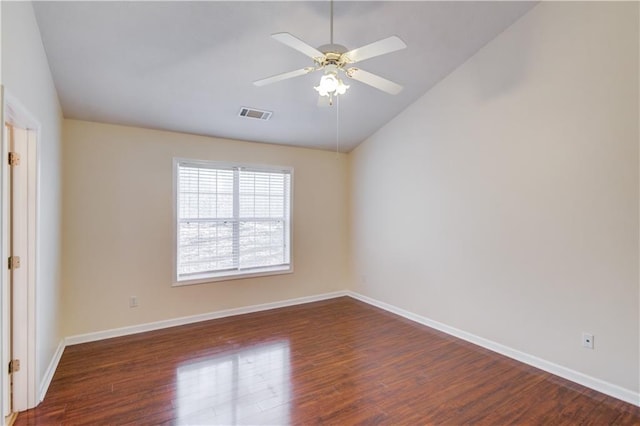 empty room featuring lofted ceiling, dark wood-type flooring, visible vents, and baseboards