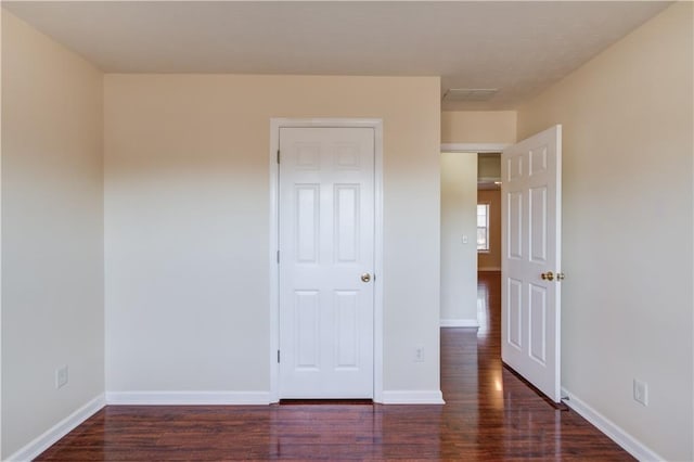 unfurnished bedroom with dark wood finished floors and baseboards